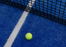 A tennis ball on a blue padel court
